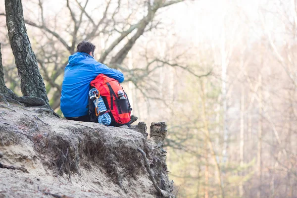 Wanderer mit Rucksack auf Felswand sitzend — Stockfoto