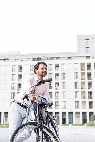 Thoughtful businessman leaning on bicycle — Stock Photo, Image