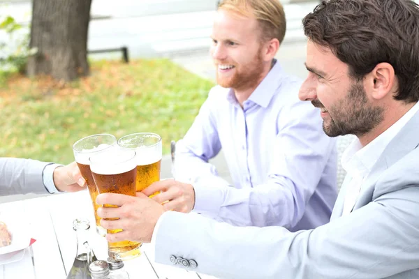 Geschäftsleute stoßen mit Biergläsern an — Stockfoto