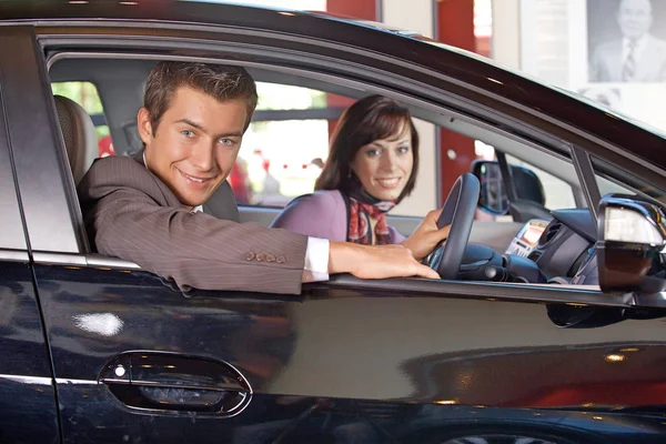 Pareja sentada en un coche nuevo en el showroom — Foto de Stock