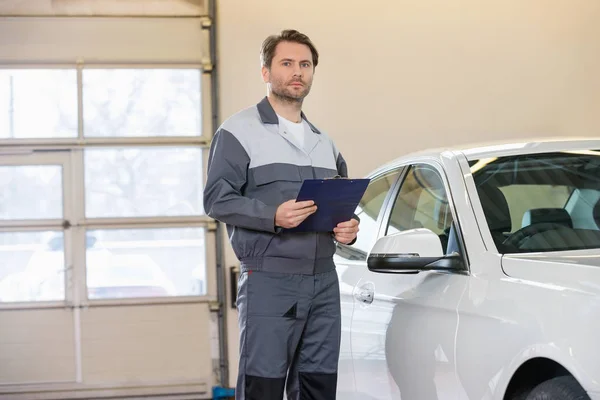 Mechaniker mit Klemmbrett in Werkstatt — Stockfoto