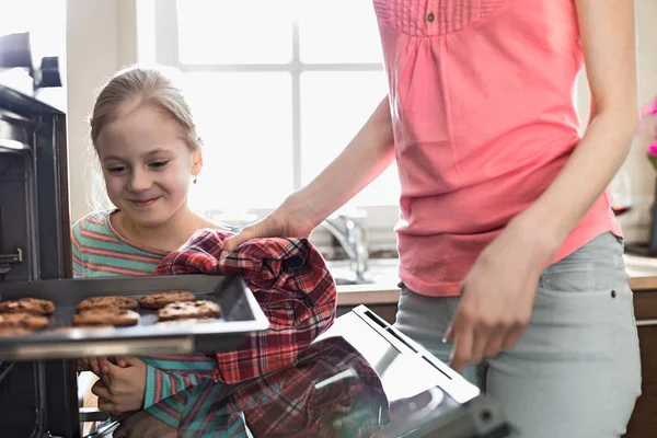 Mädchen mit Mutter beim Entfernen des Keksblechs — Stockfoto