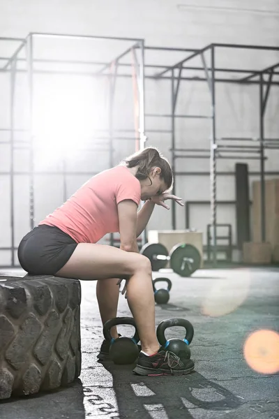 Mulher sentada no pneu no ginásio crossfit — Fotografia de Stock