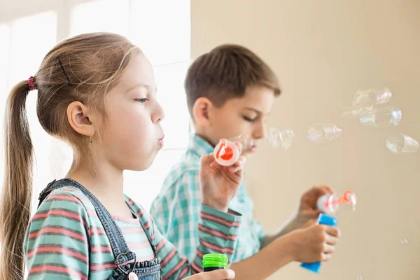 Irmão e irmã brincando com varinhas de bolha — Fotografia de Stock