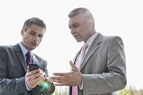 Affärsmän diskuterar över mobiltelefon — Stockfoto