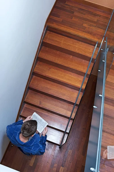 Man reading newspaper on stairs — Stock Photo, Image