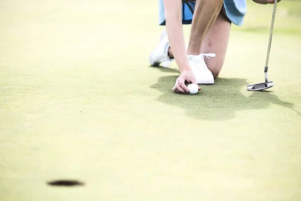 Vrouw plaatsen bal op golfbaan — Stockfoto