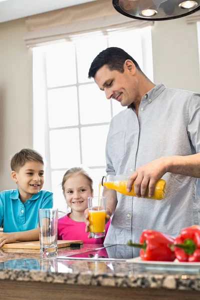 Far som serverar apelsinjuice för barn — Stockfoto