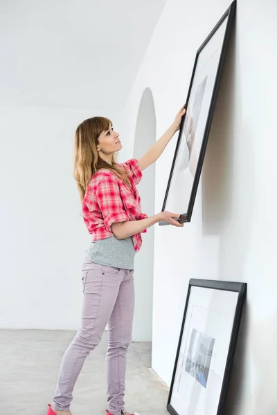 Woman hanging picture frame — Stock Photo, Image