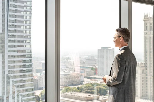 Mature businessman looking through window — Stock Photo, Image