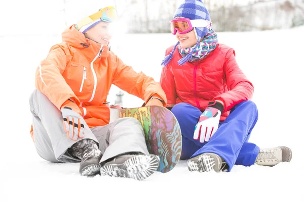Amigos do sexo feminino com snowboard relaxante — Fotografia de Stock