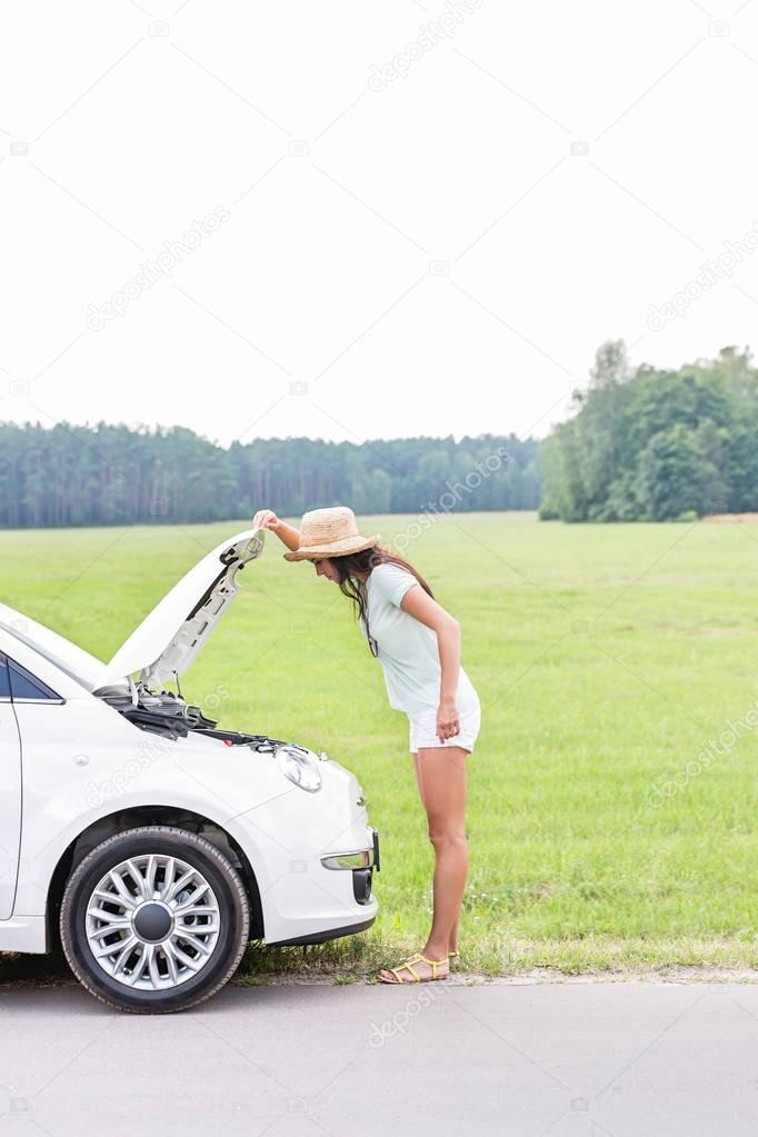 woman examining broken down car