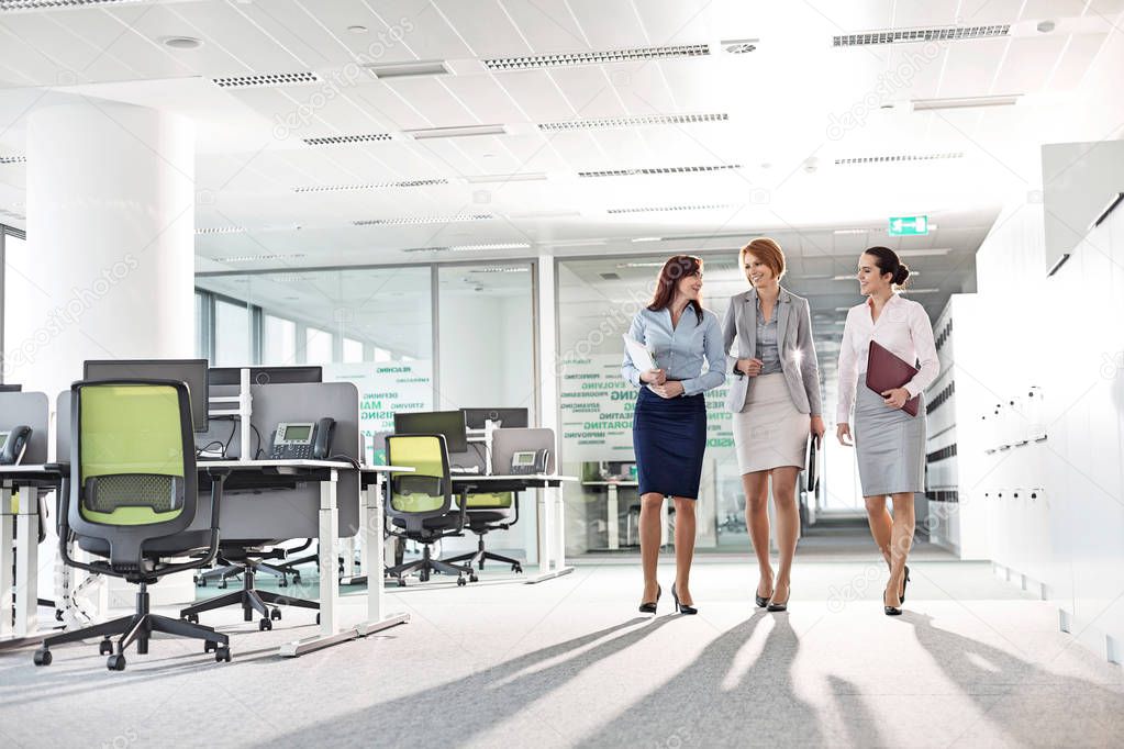 businesswomen with file folders walking in office
