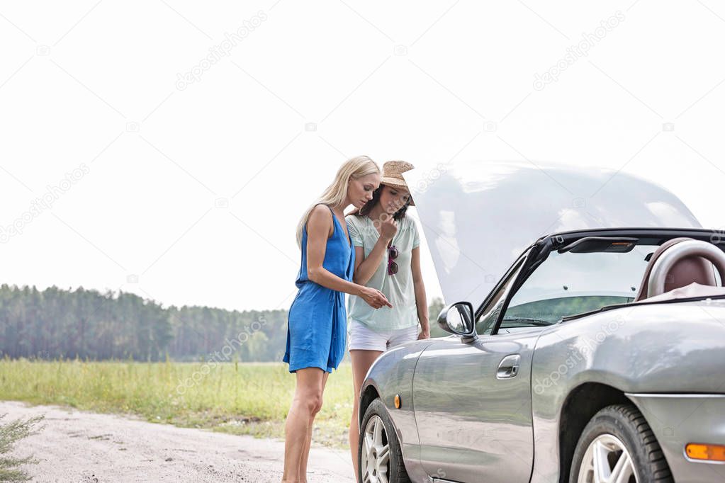 Women examining broken down car 