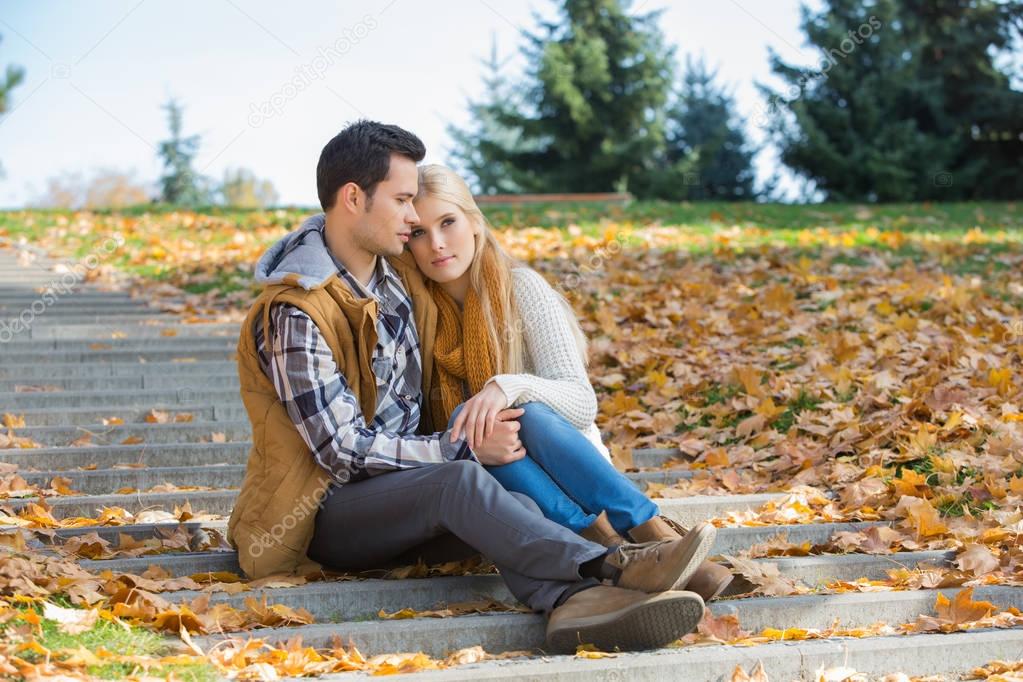 couple sitting together on steps in park 