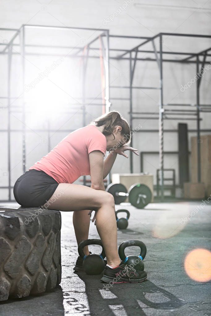 woman sitting on tire in crossfit gym