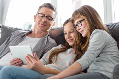 Father and daughters using tablet PC clipart