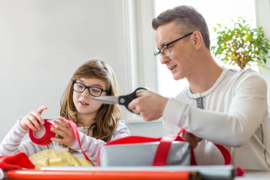 Father and daughter wrapping presents  clipart