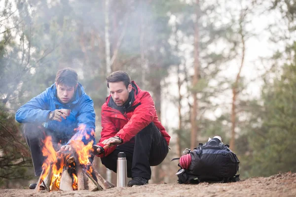 Hikers warming hands at campfire — Stock Photo, Image