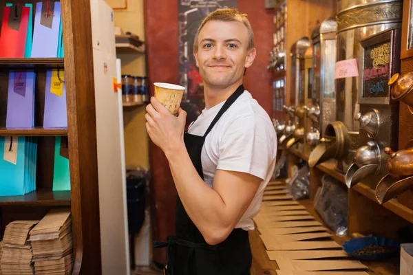 Vendedor segurando copo de café descartável — Fotografia de Stock