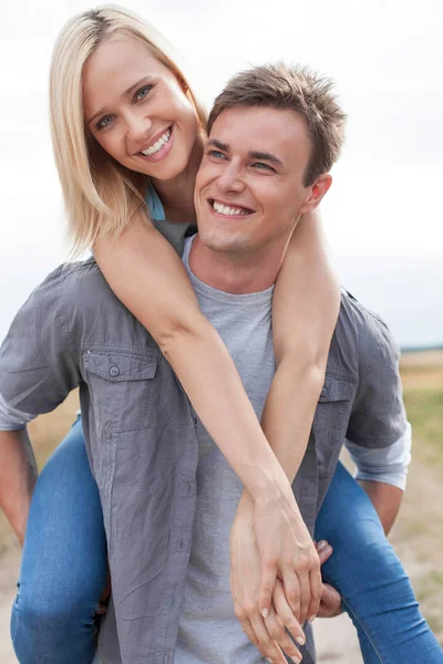 Man giving piggyback ride to woman — Stock Photo, Image