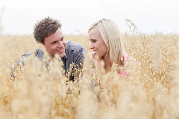 Pareja relajándose en medio del campo — Foto de Stock