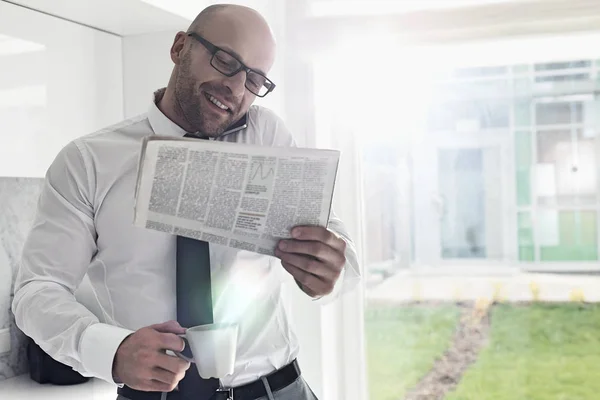 Businessman on call while holding newspaper — Stock Photo, Image