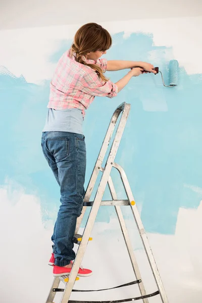 Frau auf Leiter Malwand — Stockfoto