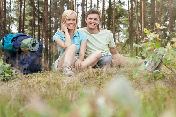 Casal com mochila relaxante na floresta — Fotografia de Stock