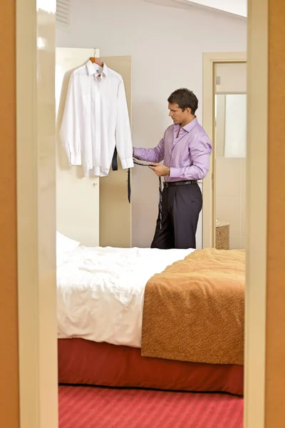 Homem segurando gravata no quarto de hotel — Fotografia de Stock