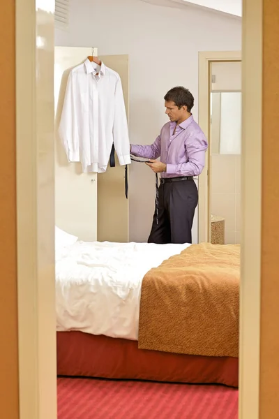 Hombre sosteniendo corbata en habitación de hotel —  Fotos de Stock