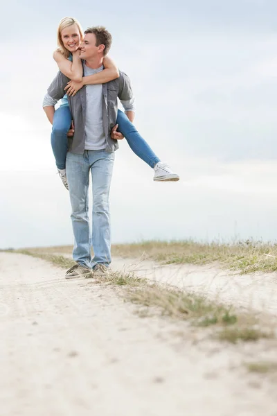 Man geven piggyback rit naar vrouw — Stockfoto