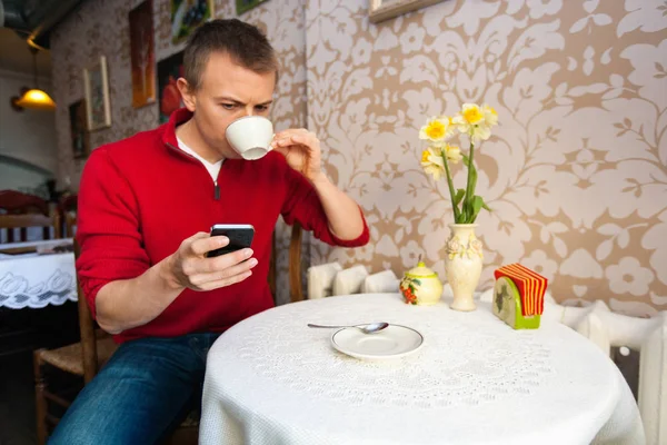 Человек пьет кофе во время обмена сообщениями — стоковое фото