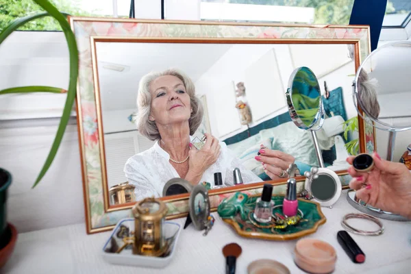 Senior woman spraying perfume — Stock Photo, Image