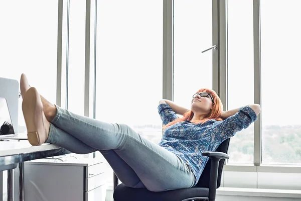 Businesswoman relaxing with feet up at desk — Stock Photo, Image