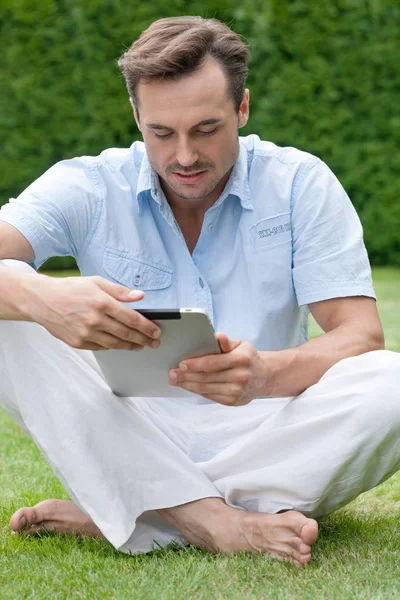 Человек с помощью цифрового планшета в парке — стоковое фото