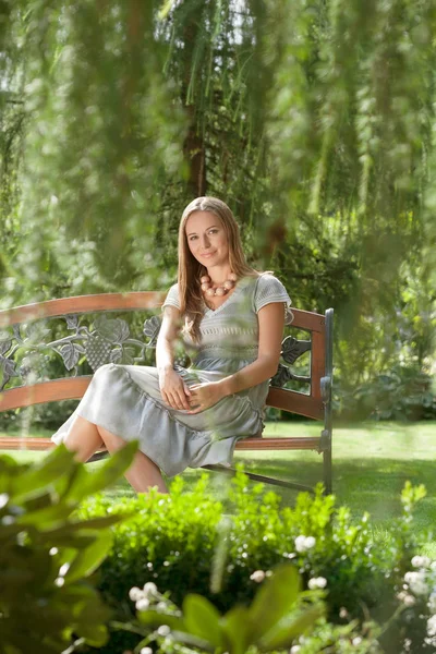 Vrouw zittend op bank in park — Stockfoto