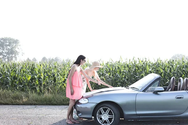 Amigos femeninos leyendo mapa en convertible — Foto de Stock