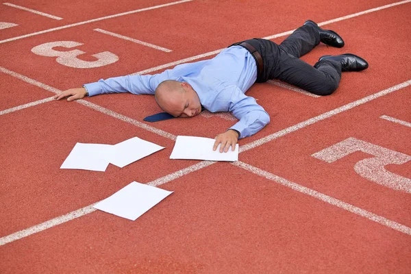 Businessman lying on a race track — Stock Photo, Image