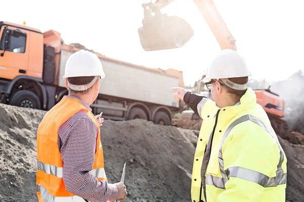 Ingenjör som pekar på fordon medan de diskuterar — Stockfoto