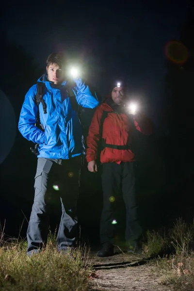 Backpackers met zaklampen in veld 's nachts — Stockfoto