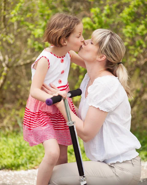 Mother and daughter kissing in park