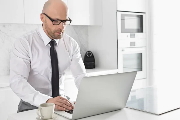 Empresário usando laptop na cozinha — Fotografia de Stock