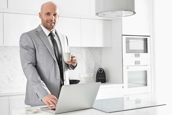 Empresário tendo café ao usar laptop — Fotografia de Stock