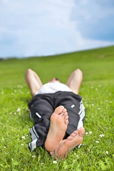 Uomo sdraiato sull'erba nel parco — Foto Stock