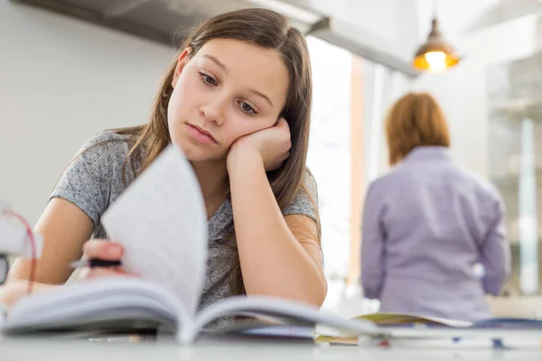 Chica aburrida estudiando en la mesa — Foto de Stock