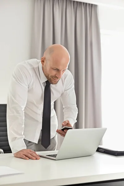 Businessman using cell phone and laptop — Stock Photo, Image