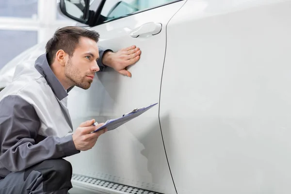 Trabajador de reparación examinando coche — Foto de Stock