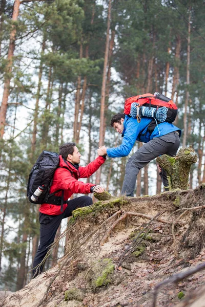 Backpacker pomáhající přítel, zatímco pěší turistika — Stock fotografie