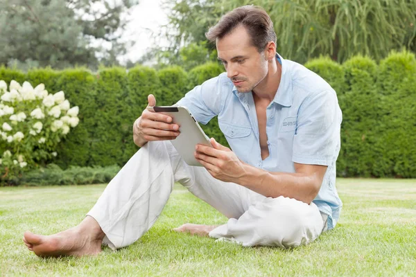 Člověk s použitím digitálního tabletu v parku — Stock fotografie